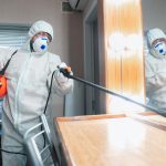 Coronavirus Pandemic. A disinfector in a protective suit and mask sprays disinfectants in the house or office