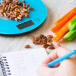 Vegetables and nuts on the scales. Calorie counting